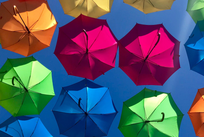 Many open umbrellas of different colors represent the heterogeneity of a work team and how important it is to have a good work environment.