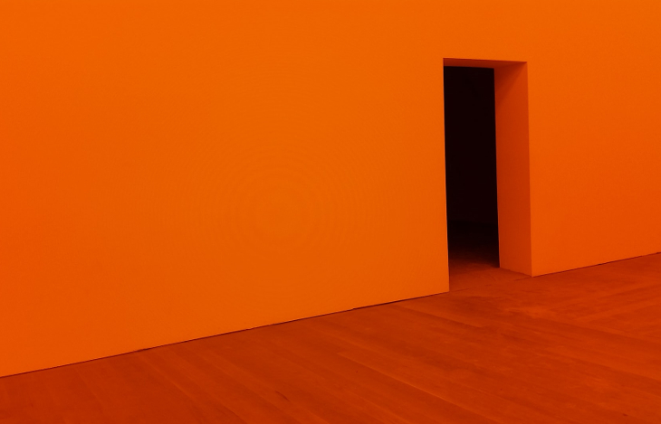 Puerta abierta en una pared naranja que simboliza la fuga de empleados de una compañía